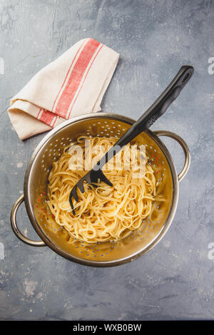 Pasta in Sieb auf grauem Hintergrund Stockfoto