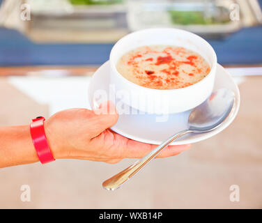 Junge Frau mit All-inclusive-Armband Halteplatte mit Suppe Stockfoto