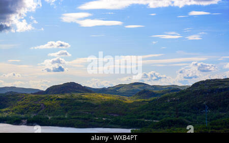 ​Blue Himmel über die Hügel in der Region Murmansk. Die niedrigen nördlichen Himmel bricht durch die Strahlen der Sonne, die sich von den Bäumen und Sträuchern. Murmansk Stockfoto