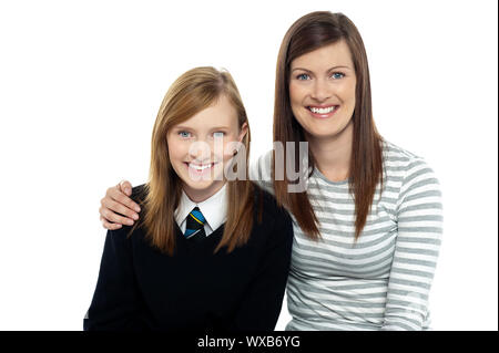 Schnappschuss von einer Mutter mit ihrer süßen Tochter gekleidet in Schuluniform in den Arm. Stockfoto