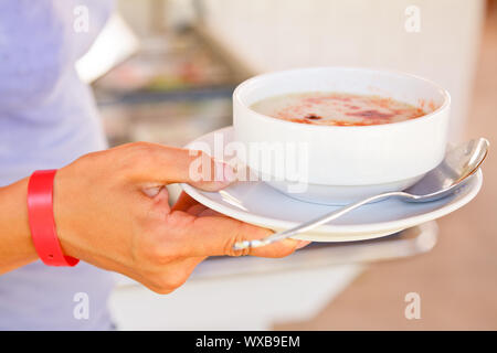 Junge Frau mit All-inclusive-Armband Halteplatte mit Suppe Stockfoto