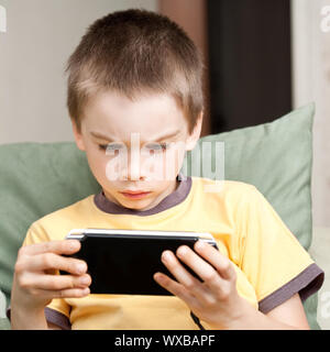 Junge Junge spielt Handheld-Konsole Stockfoto