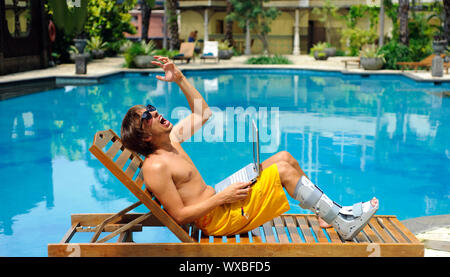 Mann mit gebrochenem Bein ist in den Schmerz am Pool Stockfoto