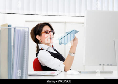 Junge Geschäftsfrau werfen Papierflieger im Büro Stockfoto
