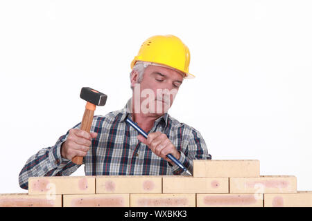 Arbeiter mit Hammer und Meißel an Wand Stockfoto