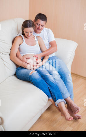 Portrait von Paar sitzt auf einem Sofa und lächelnd und in Erwartung der Kid Stockfoto