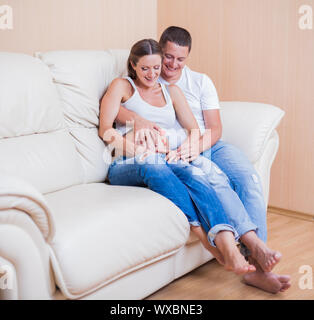 Portrait von Paar sitzt auf einem Sofa und lächelnd und in Erwartung der Kid Stockfoto