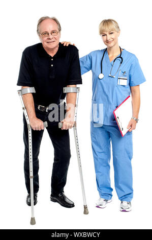 Arzt unterstützen ihren mutigen Patienten hilft ihm zu Fuß. Stockfoto