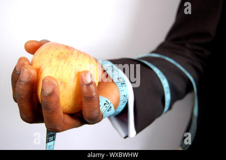 Das ist ein Bild von einem Geschäftsmann mit einem Apfel, mit einer Diät Band gebunden. Das ist eine Metapher für Ernährung, Business etc. Stockfoto