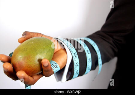 Das ist ein Bild für einen Geschäftsmann mit einer Mango, mit einer Diät Band gebunden. Das ist eine Metapher für Ernährung, Business etc. Stockfoto