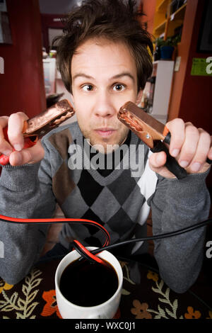 Junger Mann Betrieb Starthilfekabel aus der Kaffeetasse Stockfoto