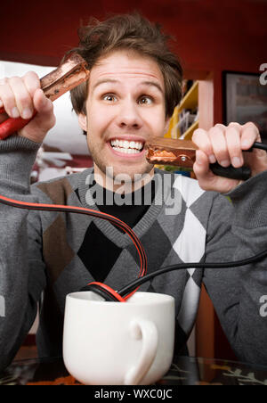 Junger Mann Betrieb Starthilfekabel aus der Kaffeetasse Stockfoto