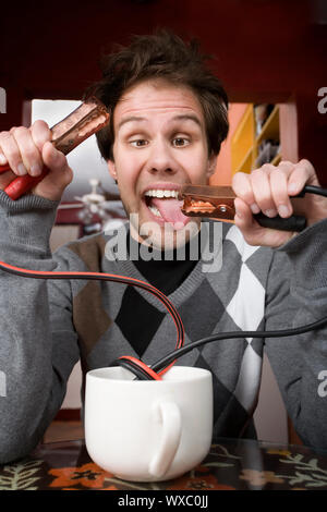 Junger Mann Betrieb Starthilfekabel aus der Kaffeetasse Stockfoto