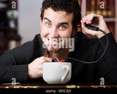 Junger Mann Betrieb Starthilfekabel aus der Kaffeetasse Stockfoto