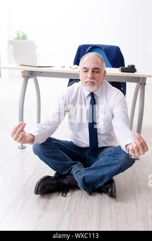 Alter Geschäftsmann Yoga Übungen im Büro Stockfoto