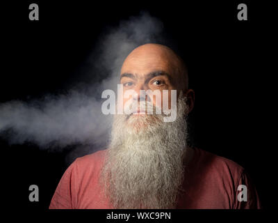Der bärtige Mann erhält Rauch in seinem Gesicht Porträt Stockfoto