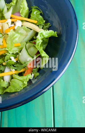 Grüner Salat in blau Schüssel auf Holztisch Stockfoto