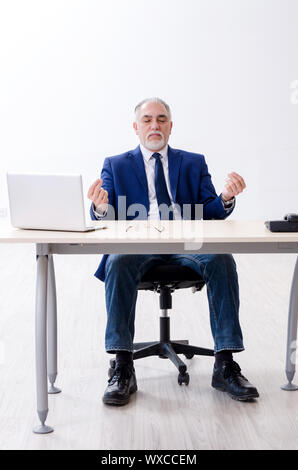 Alter Geschäftsmann Yoga Übungen im Büro Stockfoto