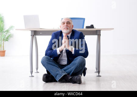 Alter Geschäftsmann Yoga Übungen im Büro Stockfoto