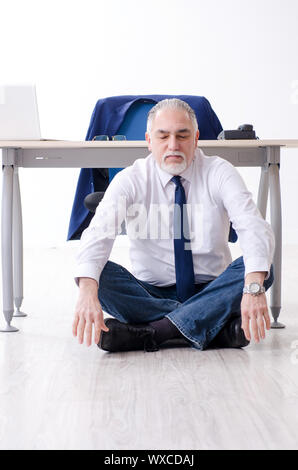 Alter Geschäftsmann Yoga Übungen im Büro Stockfoto