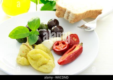 Verschiedene Oliven und Paprika auf einem weißen Teller Stockfoto