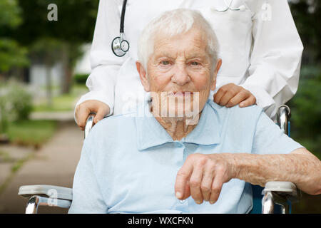 Glücklich älteren Dame im Rollstuhl mit ihrem Betreuer Stockfoto
