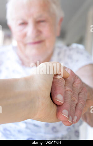 Junge hand Holding ältere Dame Hand auf der Veranda Stockfoto