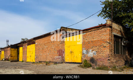 Fassade des gelben Metalls Lagerhalle, ein Geschäftshaus mit Eingängen für Autos für die Lagerung von Waren. Das Konzept der Lagerung von Waren, die die Importeure, exp Stockfoto