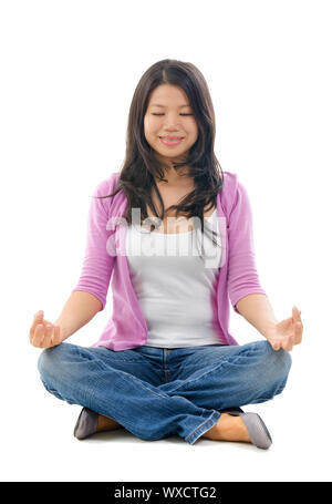 Ruhig südostasiatischen Chinesin in Yoga Lotus Pose sitzt. Voller Körper auf weißem Hintergrund. Stockfoto