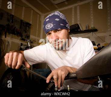 Hispanische Mechaniker arbeitet an einem Chopper-Stil-Motorrad Stockfoto