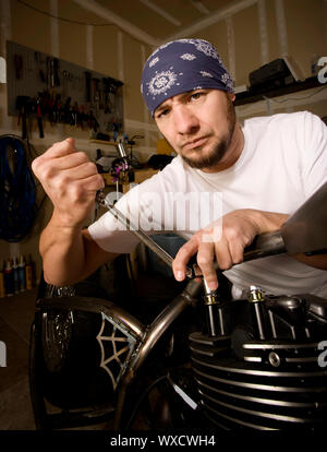 Hispanische Mechaniker arbeitet an einem Chopper-Stil-Motorrad Stockfoto