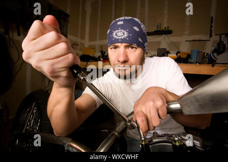 Hispanische Mechaniker arbeitet an einem Chopper-Stil-Motorrad Stockfoto