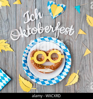 Papier Text "Ich Oktoberfest', Ansicht von oben, Quadrat Zusammensetzung Liebe. Flach auf rustikalen Holztisch mit Brezeln auf Papier Platte, dekorative Herzen, Fahnen Stockfoto