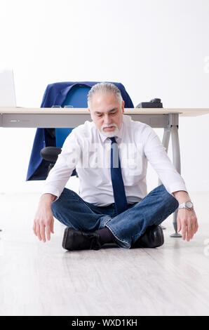 Alter Geschäftsmann Yoga Übungen im Büro Stockfoto