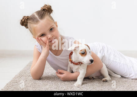 Kindheit, Haustiere und Hunde Konzept - Tited Kind Mädchen auf dem Boden mit Welpen posing Stockfoto