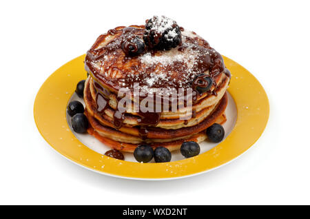Stapel von leckeren Pfannkuchen mit Brombeeren, Heidelbeeren, Schokolade und Zucker Glasur Pulver auf Gelb Platte isoliert auf weißem Hintergrund Stockfoto