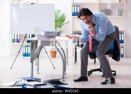 Junge männliche Mitarbeiter mit übermäßiger Arbeit unzufrieden Stockfoto