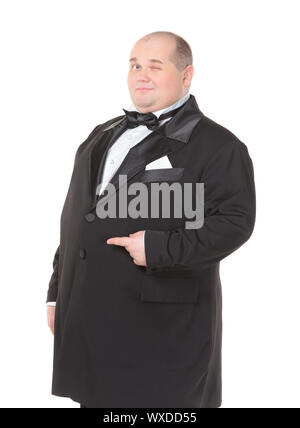 Sehr fetter Mann im Smoking und Fliege zwinkern schelmisch und zeigt mit dem Finger über seinen Bauch Elegant, drei Viertel studio portrai Stockfoto
