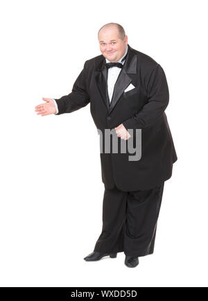 Elegante fat man in Smoking und Fliege Charmant lächelnd, wie Er hält seine Hand zur Seite und deutete in die Richtung Stockfoto