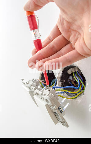 Nahaufnahme von einem Elektriker Prüfung von elektrischen Spannung an einen Lichtschalter. Stockfoto