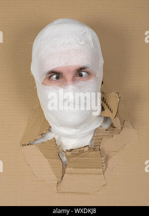 Männliche Gesicht auf die Bandage in Karton Bohrung Stockfoto