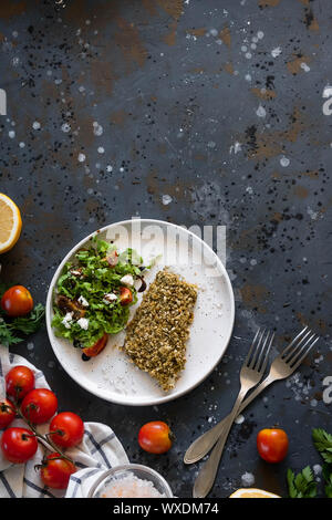 Gebackener Wolfsbarsch würzigen Panade mit frischen Salat. Ein Beispiel für ein ausgewogenes Mittagessen. Das Konzept der richtige Ernährung. Leckere, gesunde und einfache Gerichte. Stockfoto