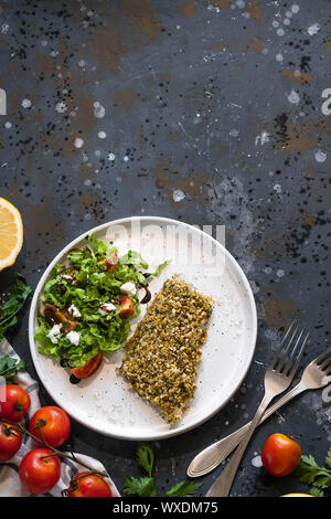 Gebackener Wolfsbarsch würzigen Panade mit frischen Salat. Ein Beispiel für ein ausgewogenes Mittagessen. Das Konzept der richtige Ernährung. Leckere, gesunde und einfache Gerichte. Stockfoto