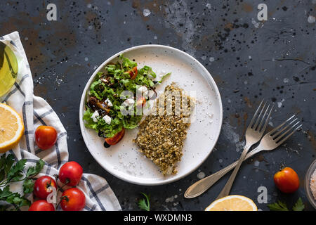 Gebackener Wolfsbarsch würzigen Panade mit frischen Salat. Ein Beispiel für ein ausgewogenes Mittagessen. Das Konzept der richtige Ernährung. Leckere, gesunde und einfache Gerichte. Stockfoto