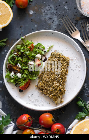 Gebackener Wolfsbarsch würzigen Panade mit frischen Salat. Ein Beispiel für ein ausgewogenes Mittagessen. Das Konzept der richtige Ernährung. Leckere, gesunde und einfache Gerichte. Stockfoto