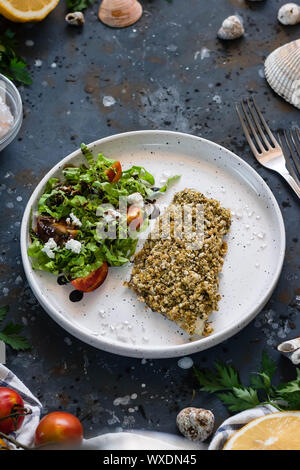 Gebackener Wolfsbarsch würzigen Panade mit frischen Salat. Ein Beispiel für ein ausgewogenes Mittagessen. Das Konzept der richtige Ernährung. Leckere, gesunde und einfache Gerichte. Stockfoto