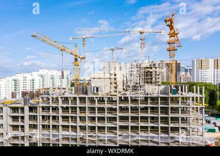 Antenne Panoramablick auf die Stadt Baustelle mit Turmdrehkrane gegen den blauen Himmel Hintergrund Stockfoto