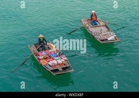 Zwei lokale saleswomen in traditionellen Boote Verkauf von Speisen und Getränken in der smaragdgrünen Wasser der Halong Bucht im Norden Vietnams. Stockfoto