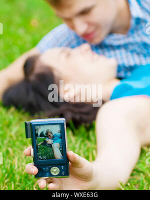 Junge emotionale Happy teenage Paar unter Bild auf Gras im City Park Stockfoto