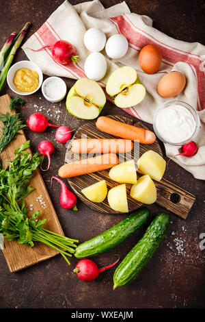 Prozess der Herstellung Okroshka Suppe. Häckseln, Rettich, Wurst und andere Zutaten auf Holz Schneidebrett Stockfoto